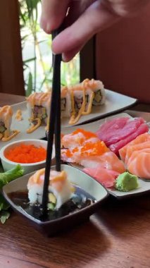 Çubuklu Kadın Eli Soya sosuna suşi batırıyor. Yakın çekim. Japon restoranının terasında somonla suşi yiyen bir kız. Yüksek kalite 4k görüntü