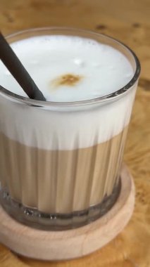 Sıcak bir kafe ortamında katmanlı kahve içmenin tadını çıkarıyorum. Yüksek kalite 4k görüntü