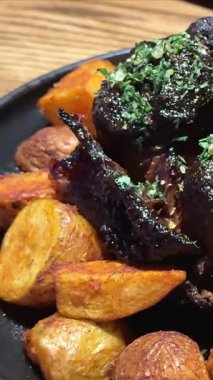 Lokanta tabağında kızarmış patates ve sos ile servis edilen ızgara kuzu pirzolası yakın çekim, yumuşak kamera hareketi. Yüksek kalite 4k görüntü