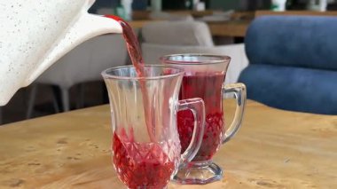 Kadın meyve sıkacağını renkli arka planda cama dolduruyor, turunçgiller kafede sağlıklı taze meyve suyu, sabah kahvaltısı içeceği. Yüksek kalite 4k görüntü