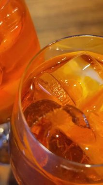  Buz küpü portakal kokteyli bardağına düşüyor. Aperol spreyi. Yüksek kalite 4k görüntü