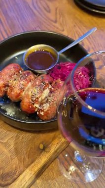 Fırında pişmiş, yaprak sebzeli ve yanında lahana turşusu salatası olan sosisleri köy masasında servis ediyoruz. Bir kadeh kırmızı şarap.