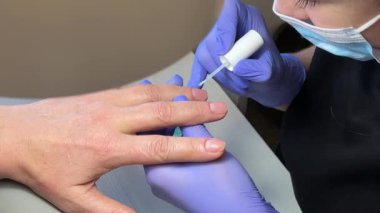 Manikürün karmaşık sürecini yakına çekerek canlı tırnak cilasının uygulanmasını, güzelliği ve kişisel ilgiyi simgeleyen bir fotoğraf. Yüksek kalite 4k görüntü