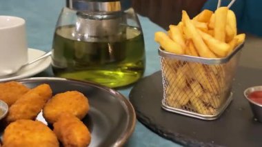 Adam bir tabak nugget ve salata alıp yerine koyuyor. Kızarmış patates kızartması.