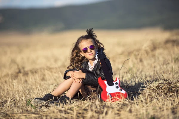 alana oturan bir oyuncak gitar ile şirin bir kız, 