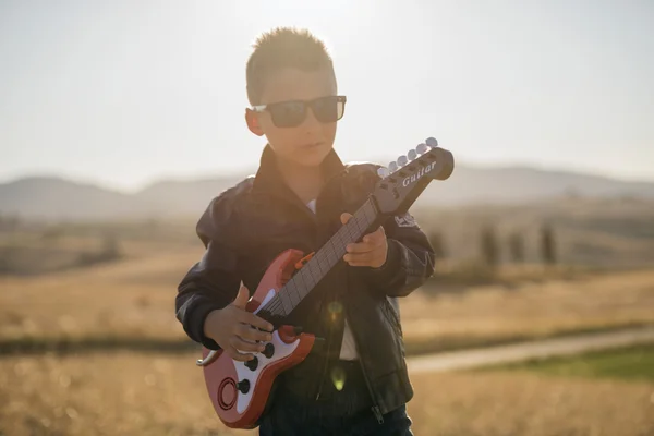 bir çocuk bir gün batımı ışık seçici odak bir oyuncak gitar çalmak