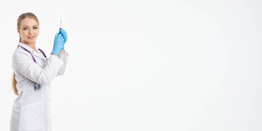 Maskeli ve beyaz önlüklü genç bir hemşire şırınga tutuyor. İğne yapmak için, grip aşısı olmak için. Aşı ve gribe karşı korunma kavramı, bir salgından. kopyalama alanı. Pankart