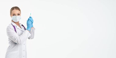 Maskeli ve beyaz önlüklü genç bir hemşire şırınga tutuyor. İğne yapmak için, grip aşısı olmak için. Aşı ve gribe karşı korunma kavramı, bir salgından. kopyalama alanı. Pankart