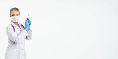 Maskeli ve beyaz önlüklü genç bir hemşire şırınga tutuyor. İğne yapmak için, grip aşısı olmak için. Aşı ve gribe karşı korunma kavramı, bir salgından. kopyalama alanı. Pankart