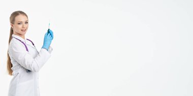 Maskeli ve beyaz önlüklü genç bir hemşire şırınga tutuyor. İğne yapmak için, grip aşısı olmak için. Aşı ve gribe karşı korunma kavramı, bir salgından. kopyalama alanı. Pankart