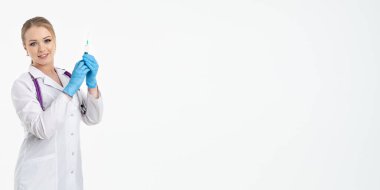 Maskeli ve beyaz önlüklü genç bir hemşire şırınga tutuyor. İğne yapmak için, grip aşısı olmak için. Aşı ve gribe karşı korunma kavramı, bir salgından. kopyalama alanı. Pankart