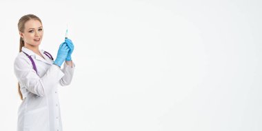 Maskeli ve beyaz önlüklü genç bir hemşire şırınga tutuyor. İğne yapmak için, grip aşısı olmak için. Aşı ve gribe karşı korunma kavramı, bir salgından. kopyalama alanı. Pankart