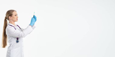 Maskeli ve beyaz önlüklü genç bir hemşire şırınga tutuyor. İğne yapmak için, grip aşısı olmak için. Aşı ve gribe karşı korunma kavramı, bir salgından. kopyalama alanı. Pankart