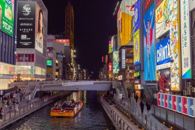 Osaka Japonya 'nın Dotonbori bölgesindeki bir kanal boyunca renkli ışıklı neon işaretler. Fotoğraf akşamleyin çekildi.