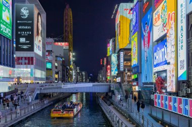 Osaka Japonya 'nın Dotonbori bölgesindeki bir kanal boyunca renkli ışıklı neon işaretler. Fotoğraf akşamleyin çekildi.