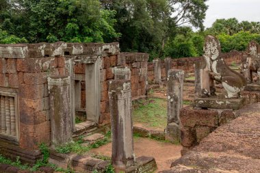 Taştan kırmızı ve tuğladan yapılmış tapınak, Siem Reap Kamboçya 'nın yemyeşil ormanlarındaki Angkor Wat tarihi yapısını harap ediyor.