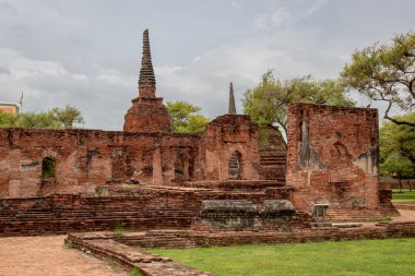 Kızıl tuğla ve taş tapınak, bulutlu bir günde Tayland 'daki Ayutthaya kentindeki Wat Phra Si Santhe tarihi mekanının pagoda kompleks binalarını yıkıyor.