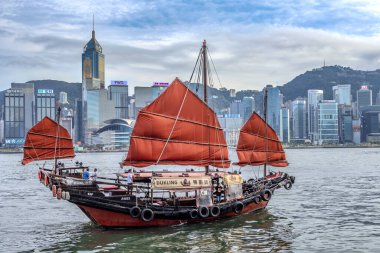 Hong Kong körfezi boyunca yüzen geleneksel tekne. Arka planda Hong Kong Victoria Adası silueti var.