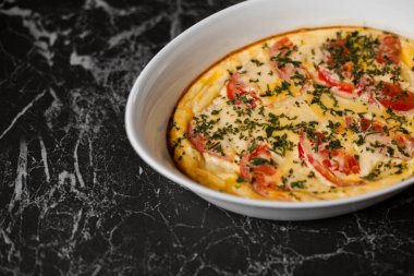 Omelet with tomatoes and cheese for breakfast in a white dish