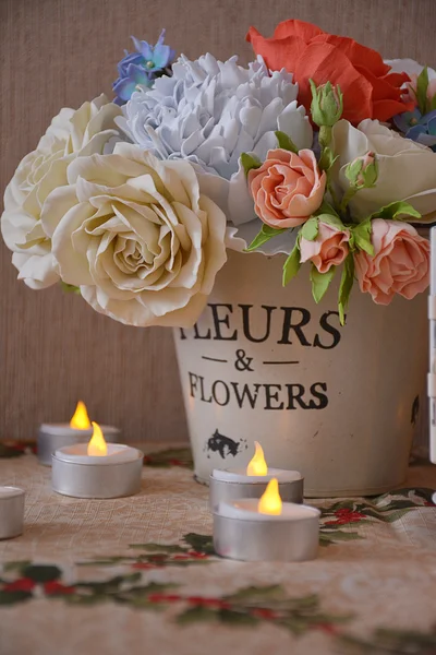 Свеча и букет цветов в декоративном ведре — стоковое фото