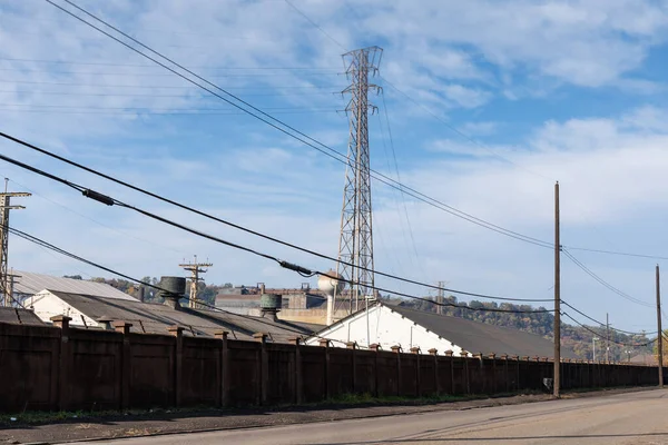 Large steel mill manufacturing facility behind a large wall, street view, horizontal aspect