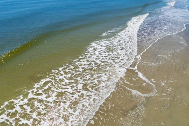 Deniz köpüğü kıyı şeridindeki alçak kristal mavi ve yeşil okyanus suları, yukarıdan, yatay açıdan görülür.