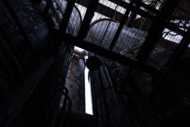 Platform ızgaralarından gökyüzüne bakarken eski çelik fabrikasının fırınları arasında, yatay olarak.