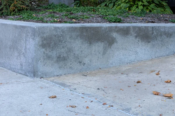 Well maintained concrete retaining wall at a corner bordered by sidewalk, horizontal aspect