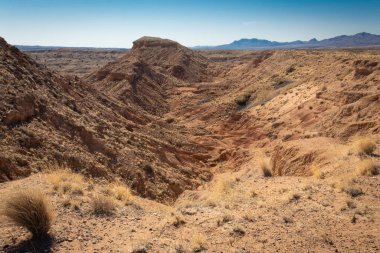 New Mexico çölündeki ağır aşınmış kanyonlara bak. Uzak dağ sırtı, yatay görünüm.