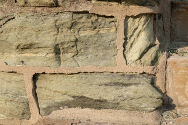 Yeşil kireç taşı ve bronzlaşmış havan taşından oluşan arka plan duvarı, erimiş taş, yatay görünüm