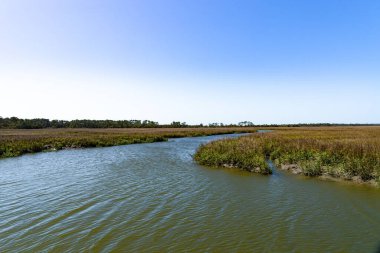 Mavi gökyüzüne sahip tuzlu bataklık su yolu gelgit sularını yatay olarak hareket ettirmeye yansır.