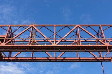 Tepedeki endüstriyel yapı kırmızıya boyanmış, canlı mavi gökyüzüne karşı izole edilmiş, yatay görünüm