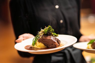 Braised pork cheeks in brown red wine sauce with mashed potatoes and vegetables. Slow cooked pork cheeks in red wine sauce with mashed potatoes.