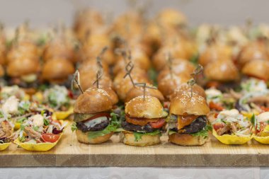 Yemek büfesinde lezzetli atıştırmalıklar. Kahve molası, iş görüşmesi. Seminerdeki iş adamı ve iş kadını için mini burgerler ve et salatası fincanları.