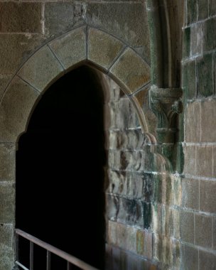Tarihi Mont Saint-Michel Manastırı 'nın içindeki Gotik taş kemer yolu. Mont Saint-Michel 'de sivri kemerli ve yıpranmış taş duvarların yer aldığı ortaçağ mimari detayları.