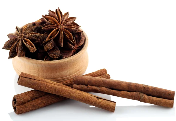 Anís estrellado en un tazón de madera con palitos de canela en una espalda blanca — Foto de Stock