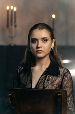 Siyah dantelli gizemli kadın dumanlı, gotik bir ortamda klasik bir piyanonun yanında poz veriyor. Yüksek kalite fotoğraf