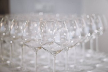 Bir sıra zarif boş şarap kadehi yumuşak odak noktasında parlıyor, zarif ve şenlikli bir atmosfer yaratıyor. Yüksek kalite fotoğraf