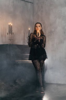 Siyah dantelli gizemli kadın dumanlı, gotik bir ortamda klasik bir piyanonun yanında poz veriyor. Yüksek kalite fotoğraf