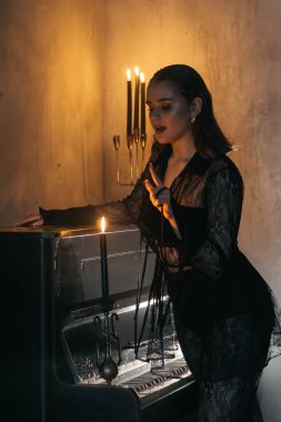 Siyah dantelli gizemli kadın dumanlı, gotik bir ortamda klasik bir piyanonun yanında poz veriyor. Yüksek kalite fotoğraf