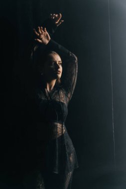 Gizemli bir kadın gölgeler ve dumanlarla çevrili parlak bir pencereye karşı siluet içinde duruyor. Yüksek kalite fotoğraf