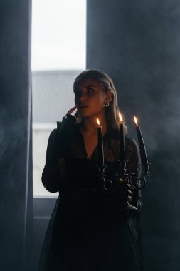 Gizemli bir kadın gölgeler ve dumanlarla çevrili parlak bir pencereye karşı siluet içinde duruyor. Yüksek kalite fotoğraf