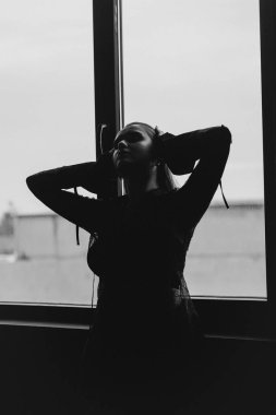 Gizemli bir kadın gölgeler ve dumanlarla çevrili parlak bir pencereye karşı siluet içinde duruyor. Yüksek kalite fotoğraf