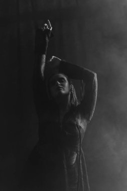 Gizemli bir kadın gölgeler ve dumanlarla çevrili parlak bir pencereye karşı siluet içinde duruyor. Yüksek kalite fotoğraf