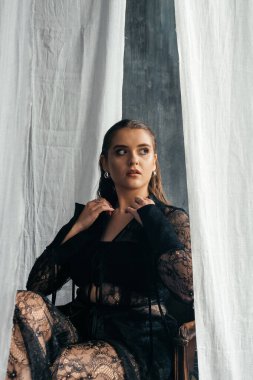 Saf siyah dantelli, kendine güvenen kadın beyaz perdeler arasında duruyor, somut güç, zarafet ve modern gotik moda. Yüksek kalite fotoğraf