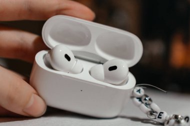 Açık bir şarj kutusunda bir çift kablosuz kulaklık tutan kişi, günlük teknolojik kullanım ve taşınabilirliği vurguluyor. Yakın plan çekimde kolaylık, modern yaşam tarzı ve kişisel ses vurgulandı