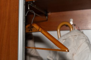 Açık bir gardırop, ahşap askılar açık renkli bir ceket ve şemsiye ile günlük depolama sahnesini yakalıyor. Görüntü organizasyonu, giysi bakımını ve ev yaşamını yansıtıyor.