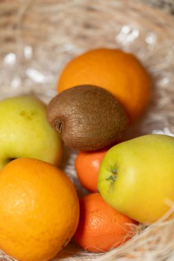 Taze meyve, elma, portakal, mandalina ve dokuma sepetine yerleştirilmiş kivi çeşitleri. Görüntü, doğal tazeliği, sağlıklı beslenmeyi ve organik yaşam tarzını yansıtıyor. Yüksek kalite