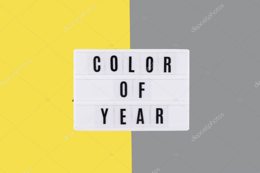 Yellow illuminating and Gray background. Flat lay, top view. Lightbox with text Color of year.