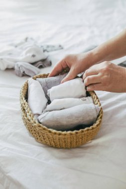 Kadın konmari sisteminde jüt sepetinde çamaşır katlıyor. Minimalizm giysileri düzenleme kavramı